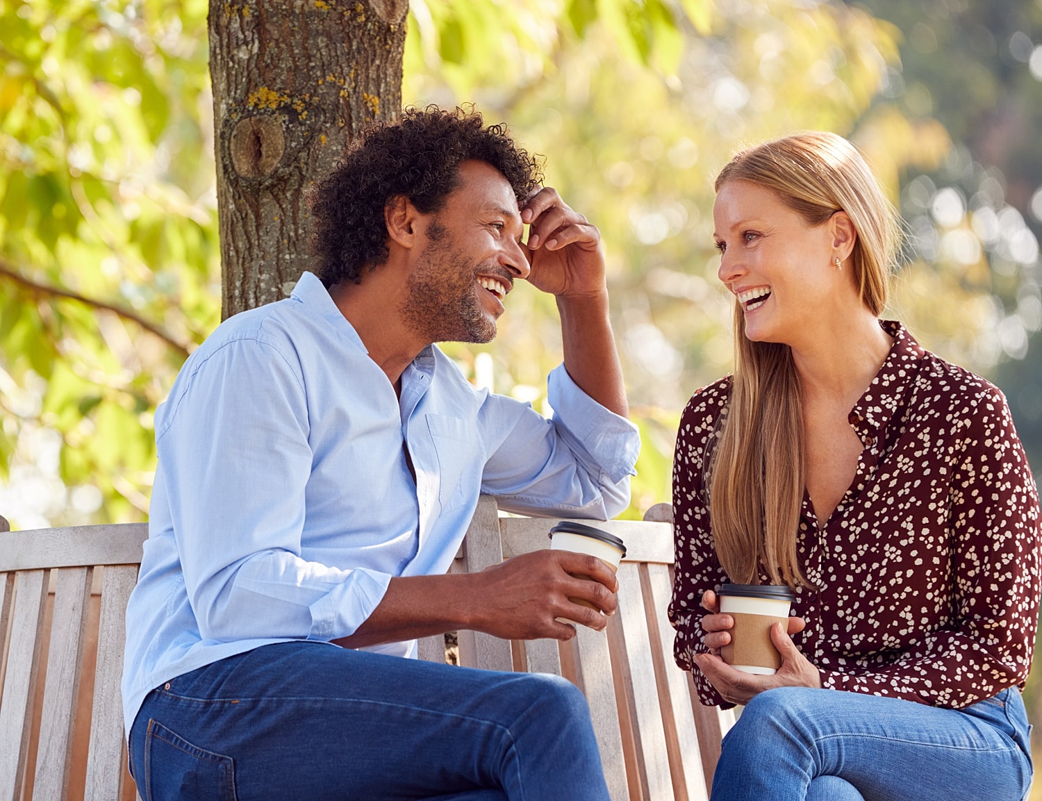 Couple enjoying coffee and laughter in nature.