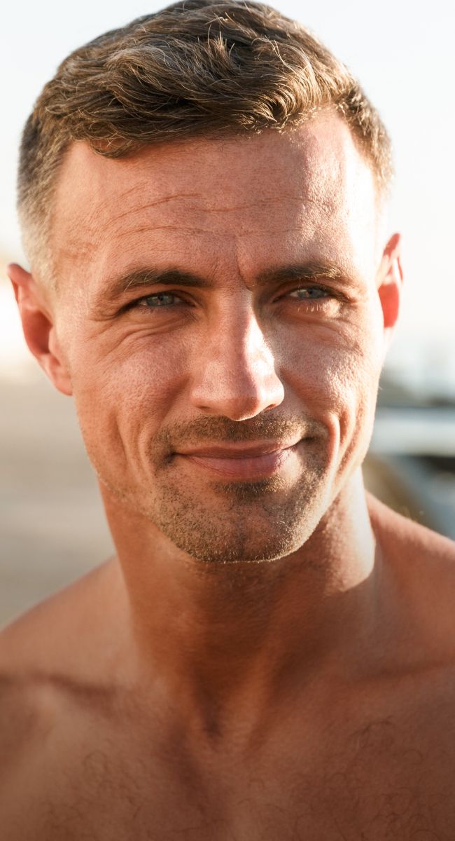 Smiling man with short hair outdoors.