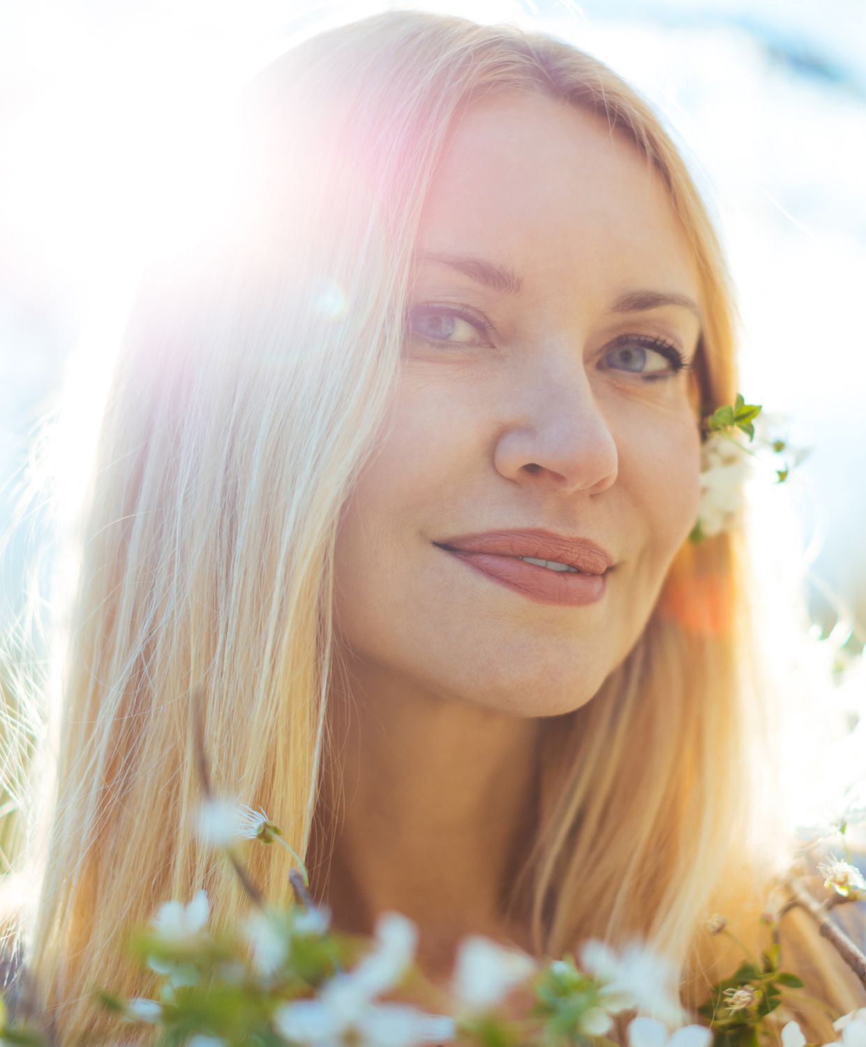 Woman with long hair surrounded by flowers.