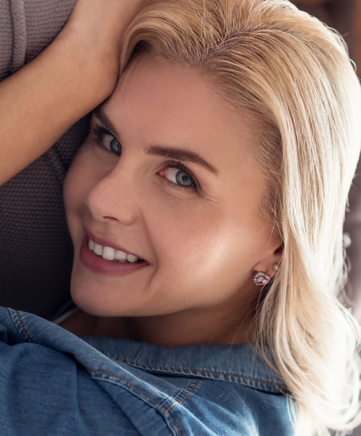 Smiling woman with blonde hair and denim shirt.