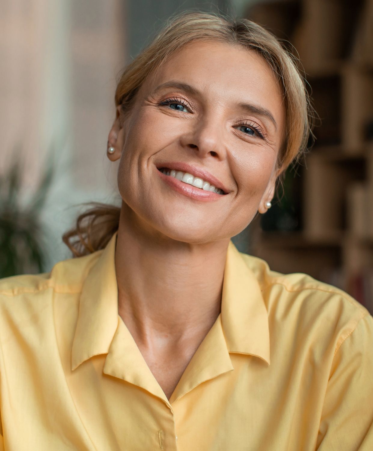 Smiling woman in yellow shirt indoors.
