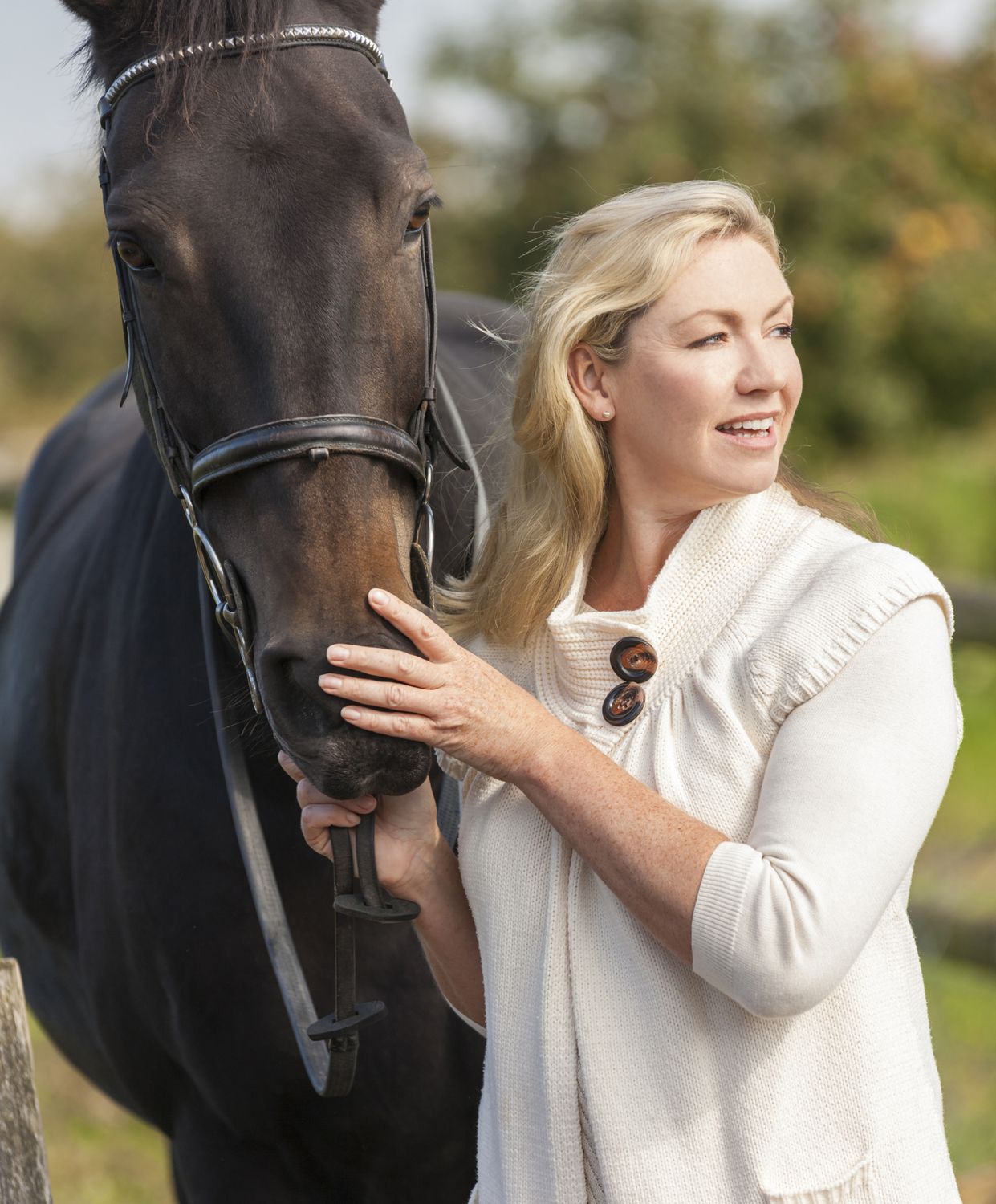 Woman gently interacting with horse outdoors.