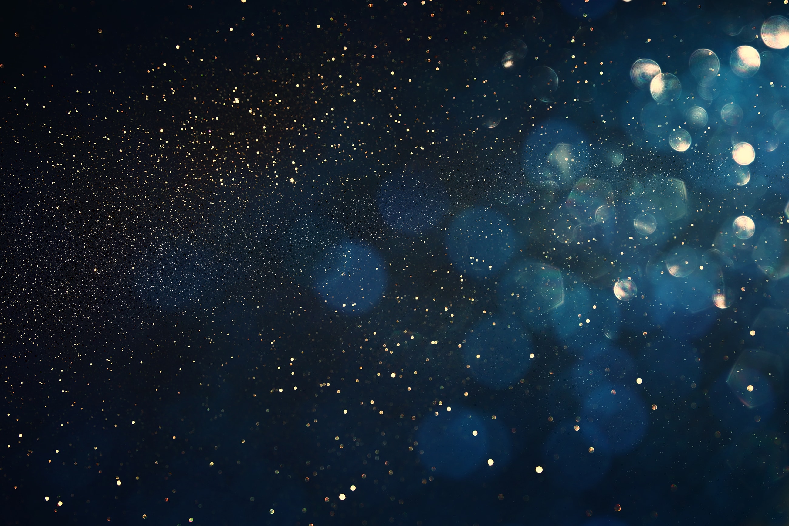 Glittering particles against a dark background.