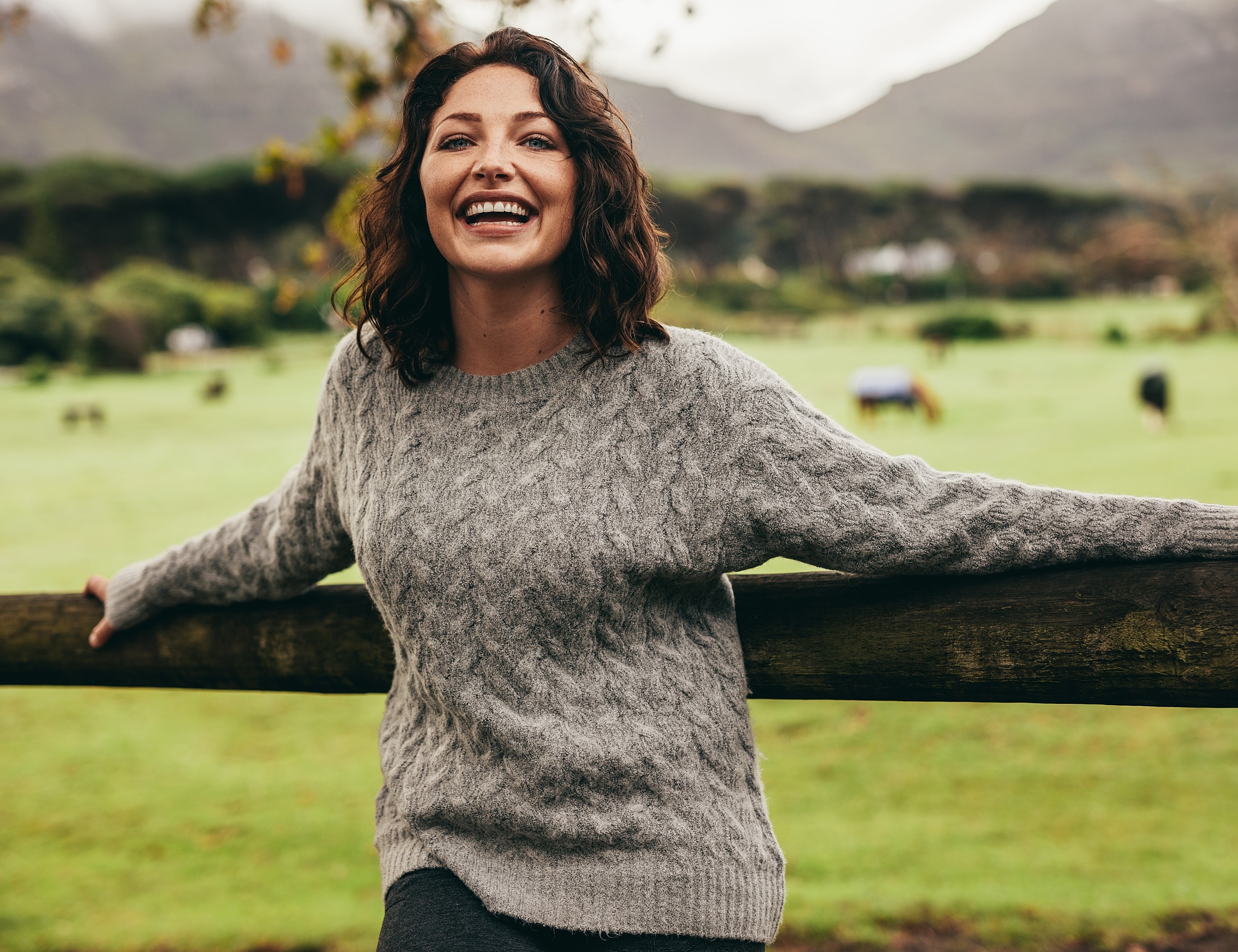 Smiling woman in cozy sweater outdoors.