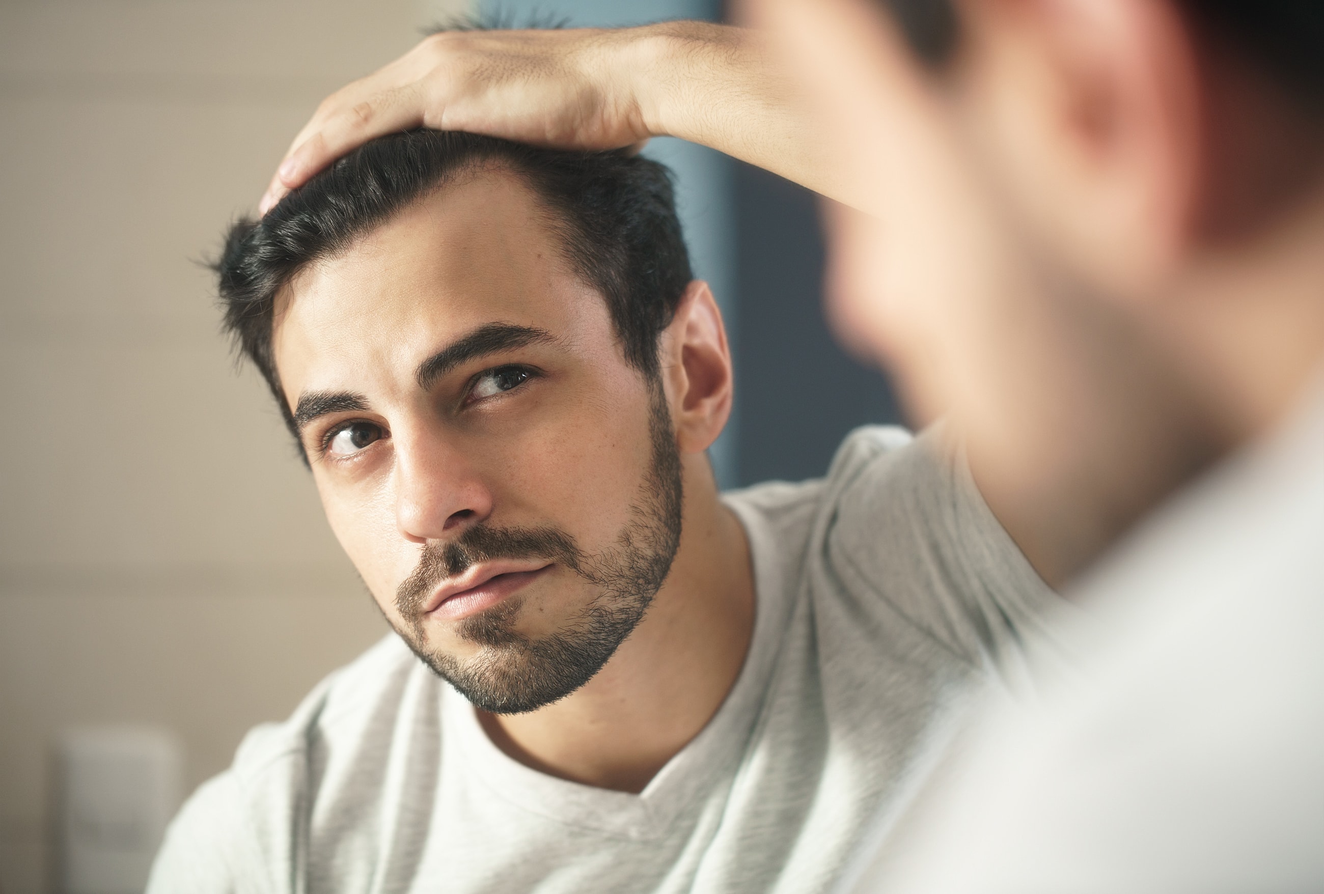 Man grooming his hair in front of a mirror.