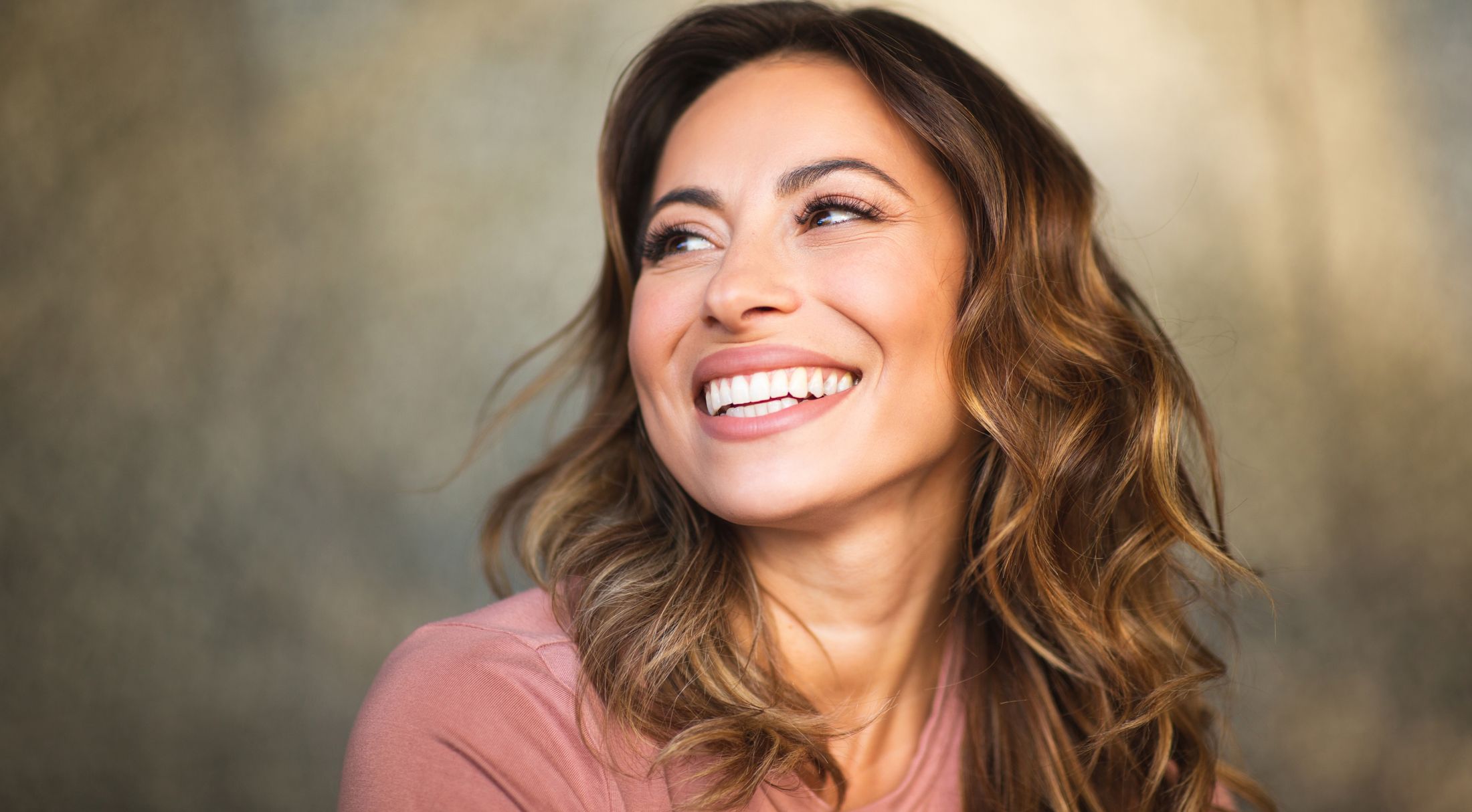 Smiling woman with wavy hair and pink shirt