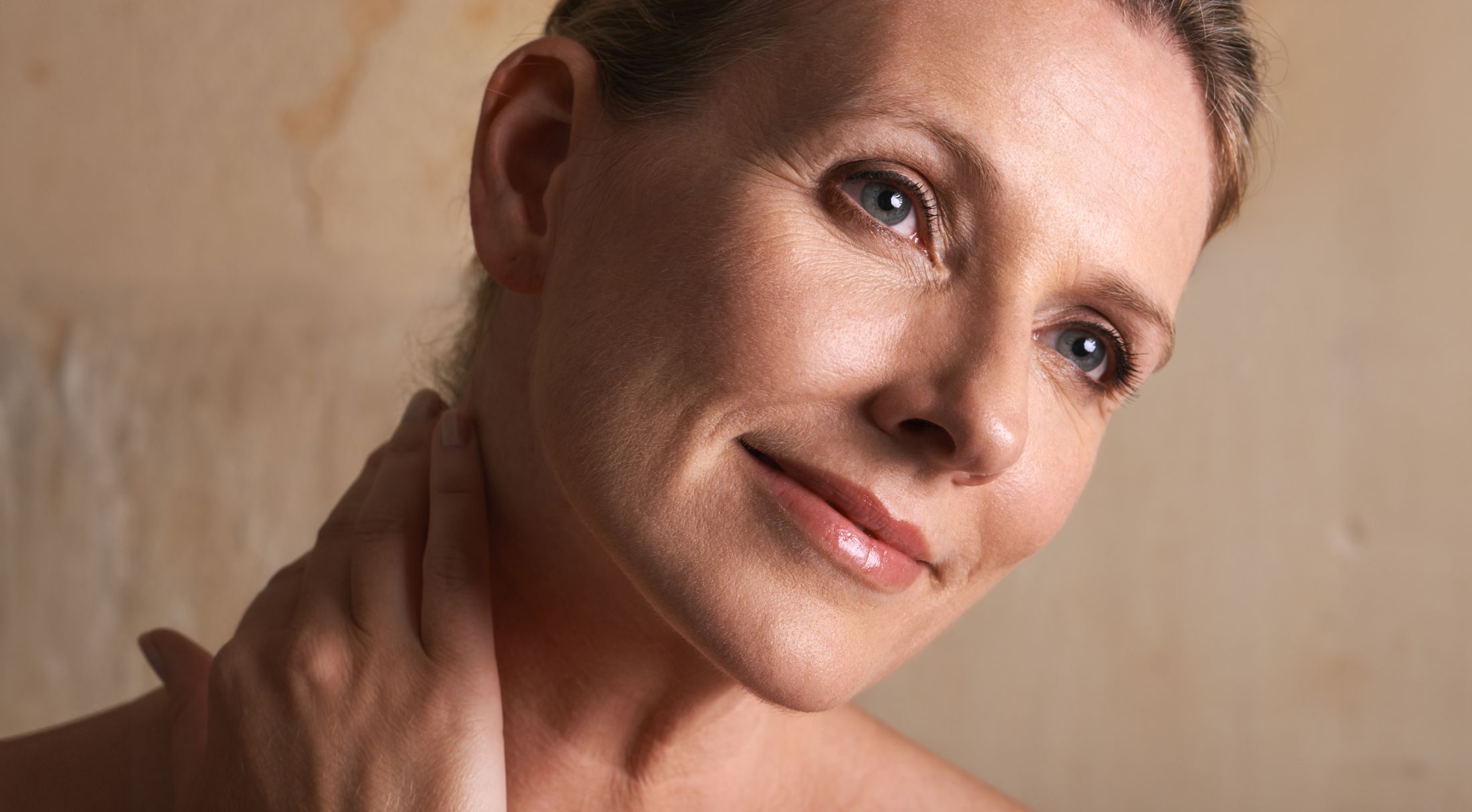 Smiling woman touching her neck softly