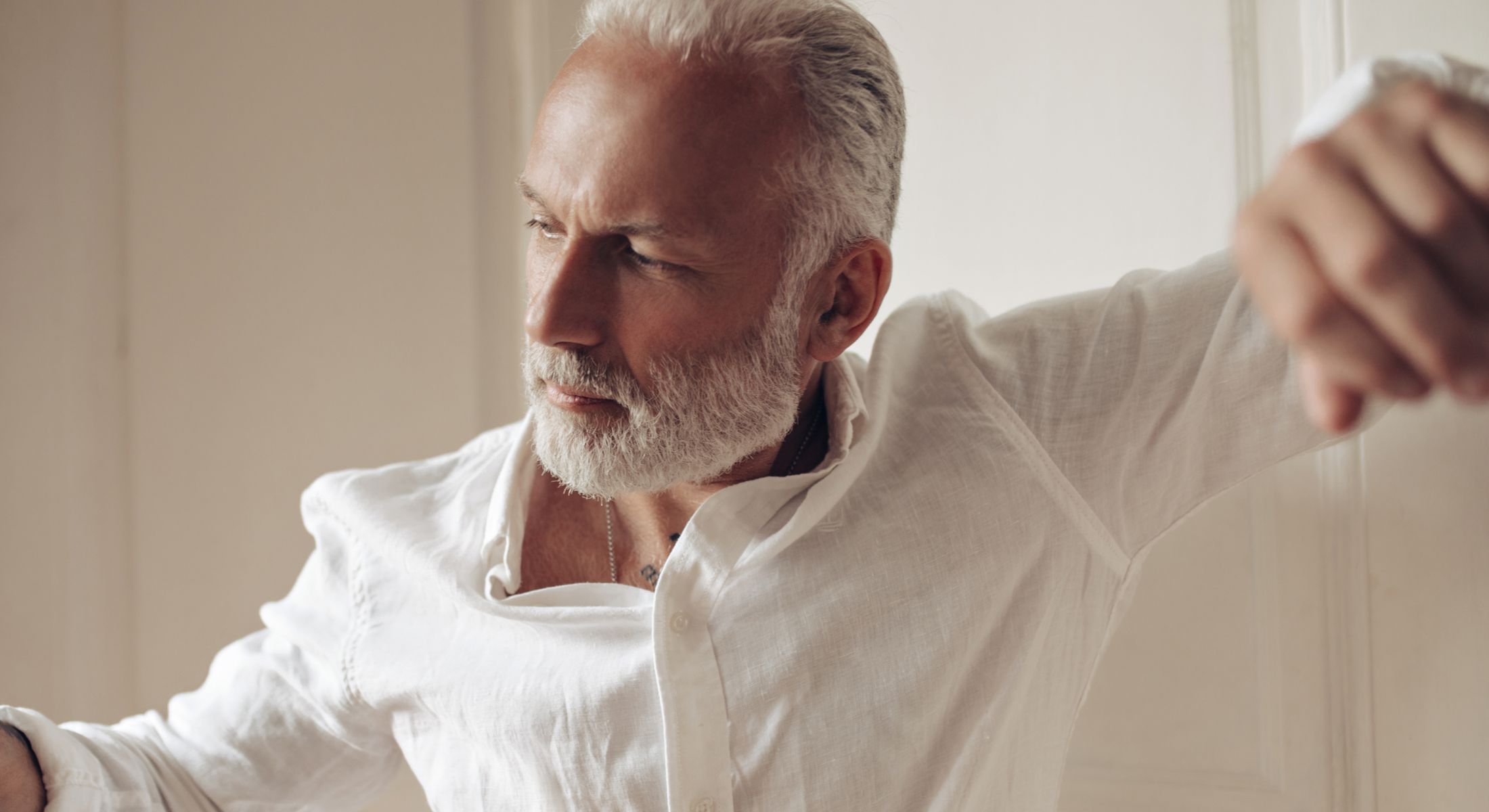 Mature man in white shirt, thoughtful expression.