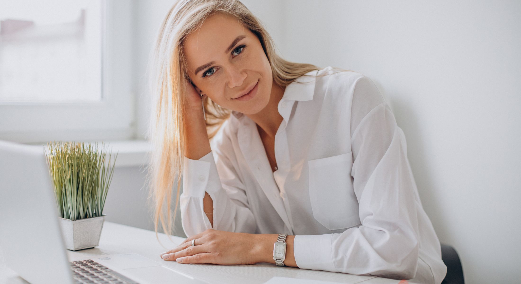 Smiling woman with long hair at a desk.
